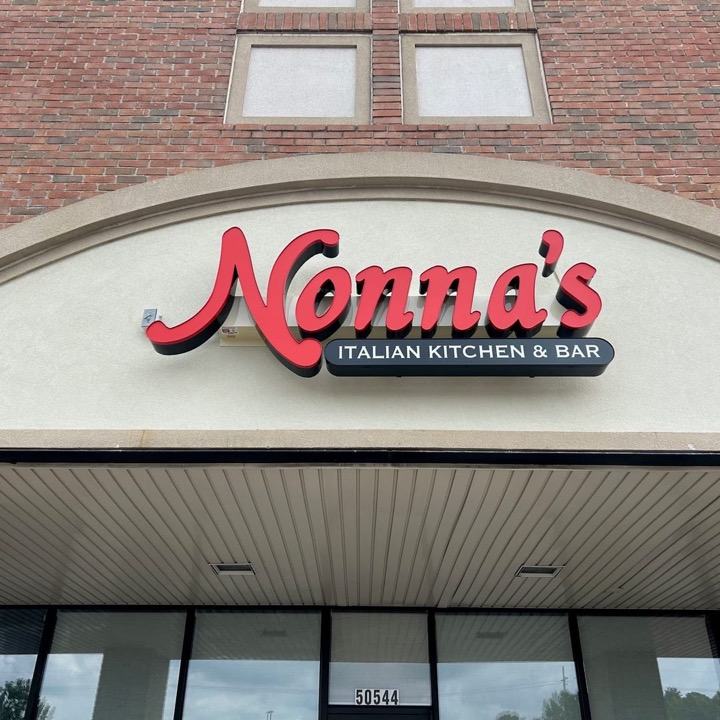 Red script Nonna's channel letters over an Italian Kitchen and Bar panel on a storefront