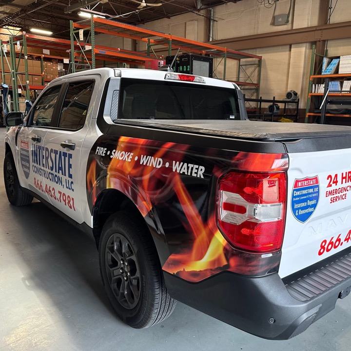 A white pickup wrapped in flames with the words Fire, Smoke, Wind and Water