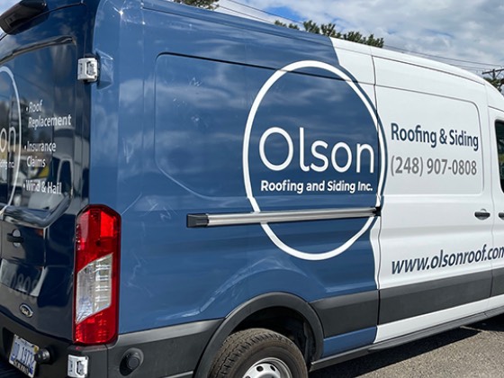 Olson Roofing and Siding van wrapped in a two-tone blue design with a circle logo