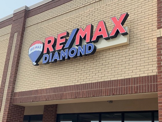 RE/MAX Diamond channel letters in red and blue mounted on a brick storefront