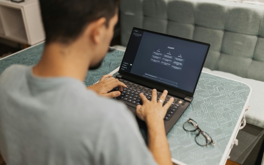 A small business owner typing into an AI chat tool on a laptop