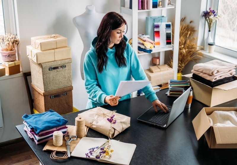 A small business owner packing orders beside her laptop