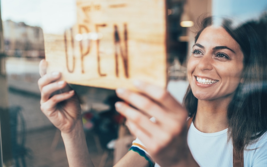 A shop owner turning the sign on her door to Open